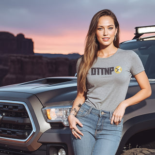 OTTNP Female Model standing next to a Toyota Tacoma in the Utah desert wearing a grey OTTNP t-shirt. ottnp.com