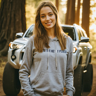 Light grey OTTNP hoodie with female model standing in front of a Toyota 4Runner. ottnp.com