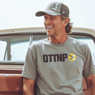 A man standing next to his truck wearing our medium grey FlexFit OTTNP Logo hat and a grey OTTNP Circle Logo t-shirt. ottnp.com